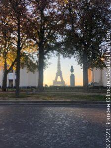 The Eiffel Tower at daybreak with a cobblestone street and trees